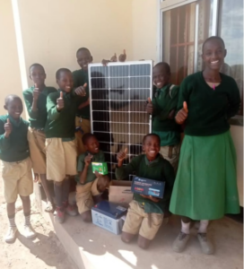 A group of children smile while presenting Ndinyika Primary School’s new solar system panel