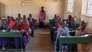 People sitting inside a classroom with tables arranged in rows